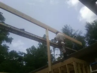 Carpenter setting a ridge beam over a new addition frame — Ice Dam Removal by Roofing Brothers in Castile