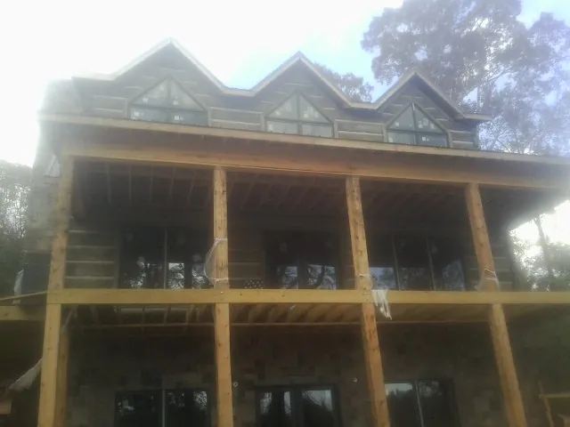 Dormers and porch framing on a large log home under construction — Roof Coating work by our crew in Castile