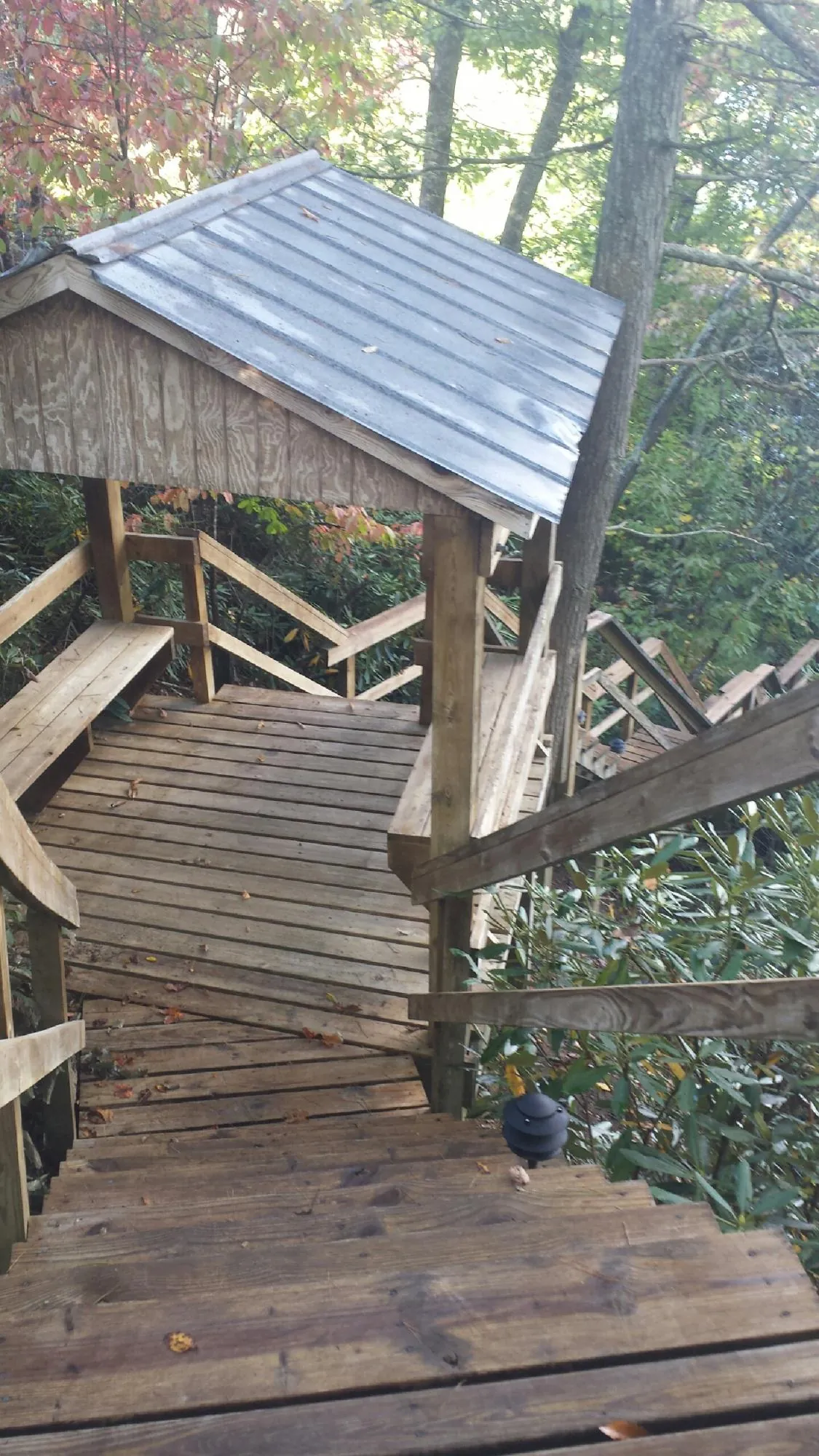 Metal roofed shelter over wooden steps on a wooded walkway — Skylight Repair & Installation work by our crew in Castile