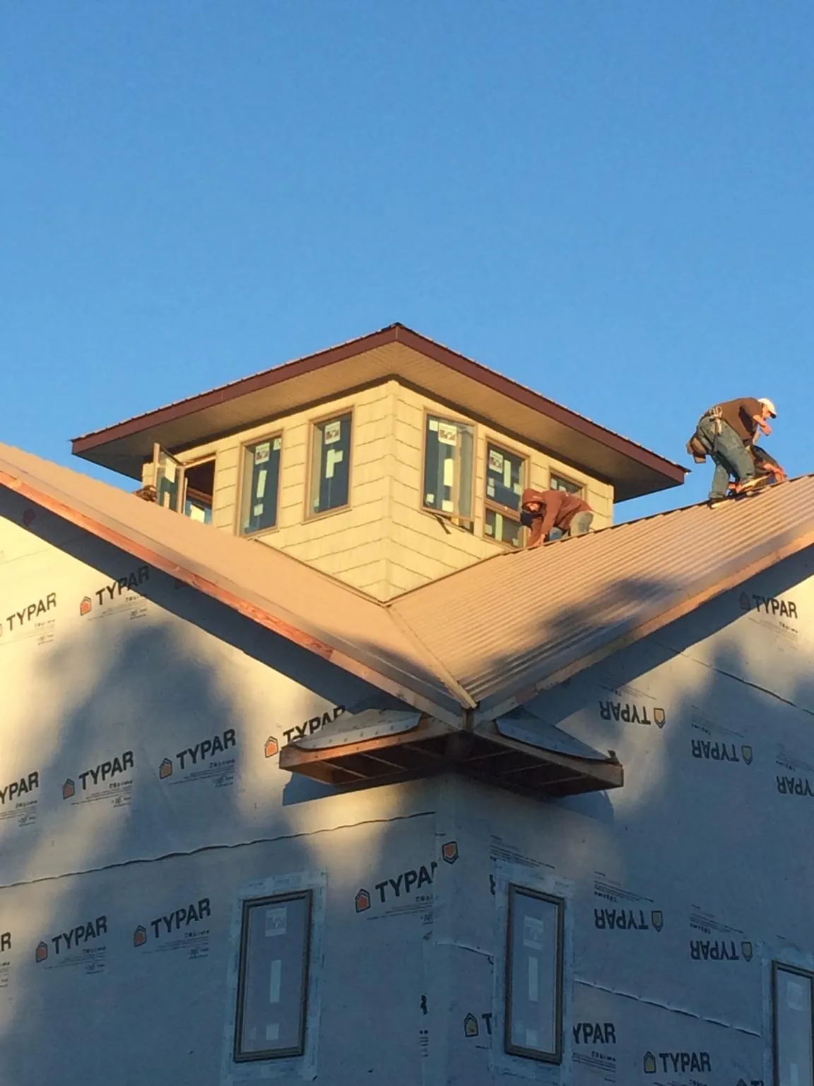 Roofers working around a rooftop cupola on a new metal roof at sunset — Roof Waterproofing in Castile by Roofing Brothers